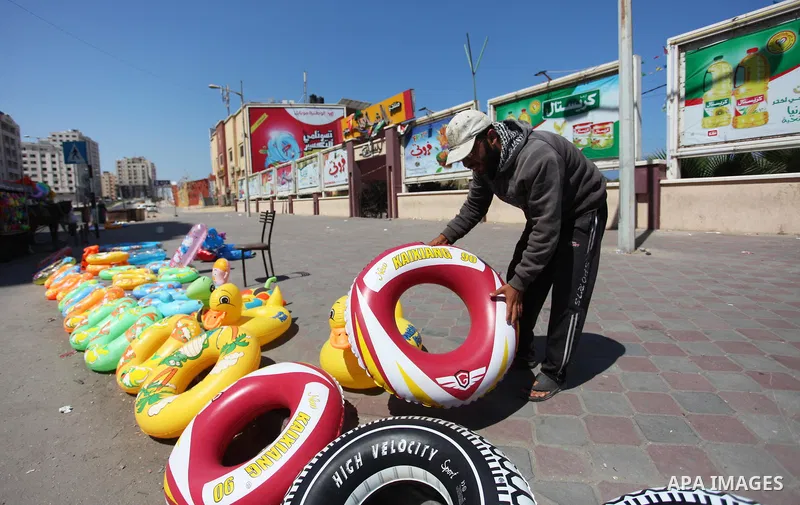 A Palestinian man displays summer games and tires at a street in Gaza city, on July 31, 2018. Photo by Mahmoud Ajour
