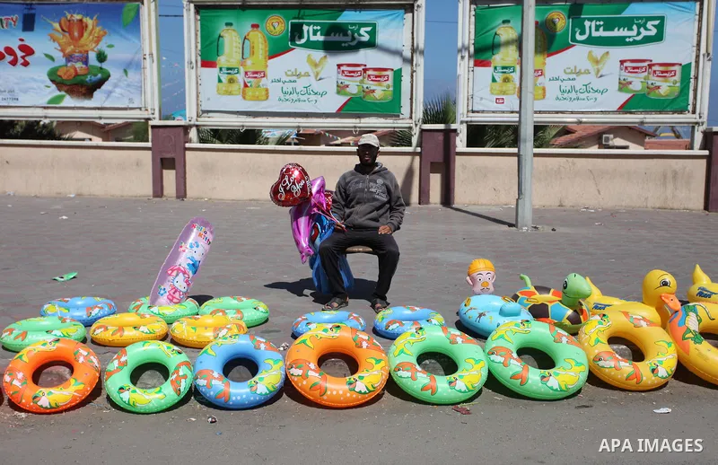 A Palestinian man displays summer games and tires at a street in Gaza city, on July 31, 2018. Photo by Mahmoud Ajour