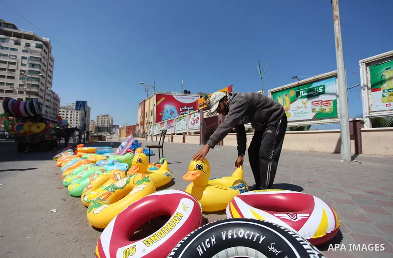 A Palestinian man displays summer games and tires at a street in Gaza city, on July 31, 2018. Photo by Mahmoud Ajour