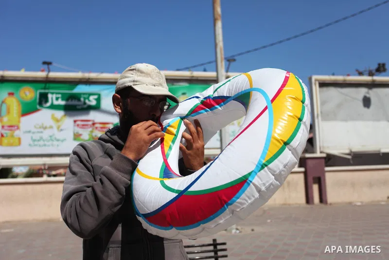 A Palestinian man displays summer games and tires at a street in Gaza city, on July 31, 2018. Photo by Mahmoud Ajour