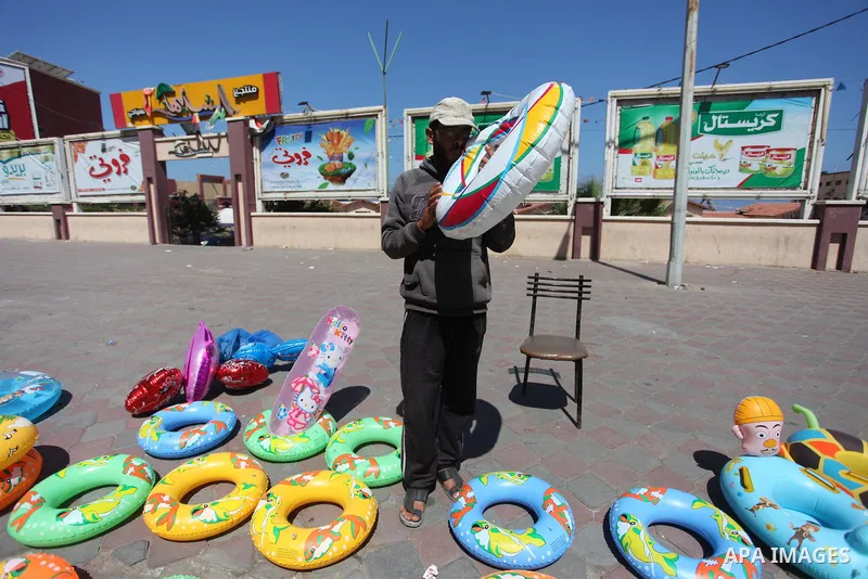 A Palestinian man displays summer games and tires at a street in Gaza city, on July 31, 2018. Photo by Mahmoud Ajour