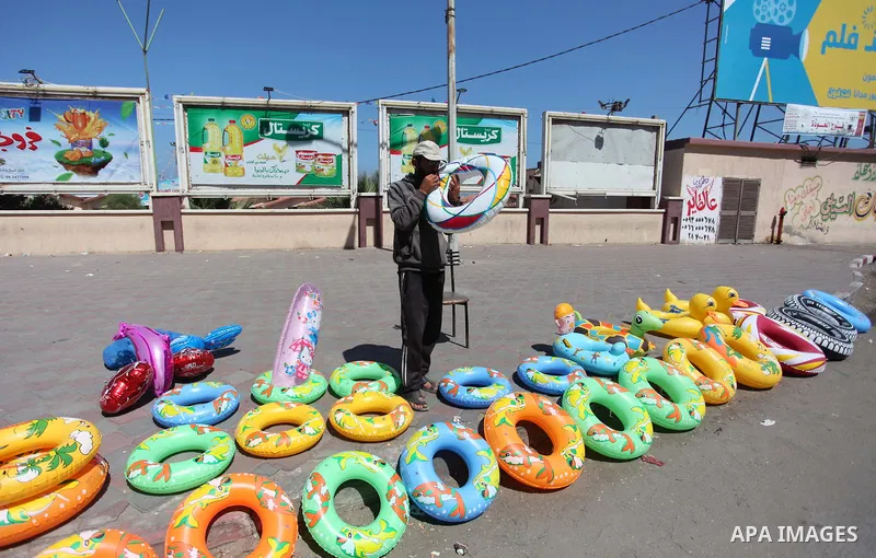 A Palestinian man displays summer games and tires at a street in Gaza city, on July 31, 2018. Photo by Mahmoud Ajour
