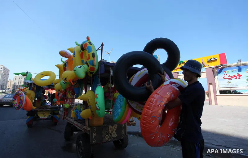 A Palestinian man displays summer games and tires at a street in Gaza city, on July 31, 2018. Photo by Mahmoud Ajour