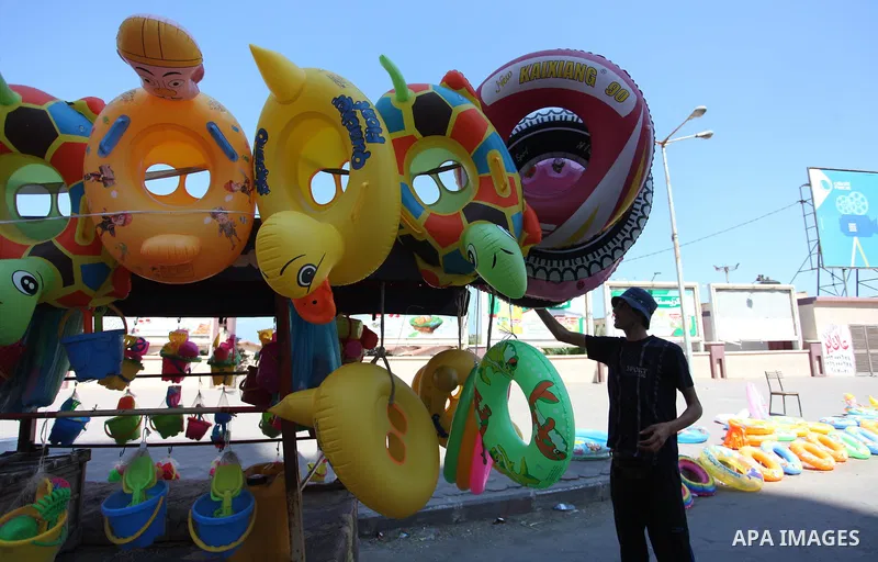A Palestinian man displays summer games and tires at a street in Gaza city, on July 31, 2018. Photo by Mahmoud Ajour