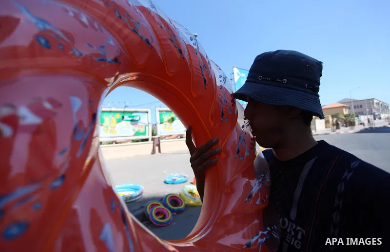 A Palestinian man displays summer games and tires at a street in Gaza city, on July 31, 2018. Photo by Mahmoud Ajour
