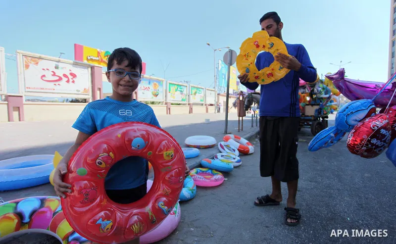 A Palestinian man displays summer games and tires at a street in Gaza city, on July 31, 2018. Photo by Mahmoud Ajour
