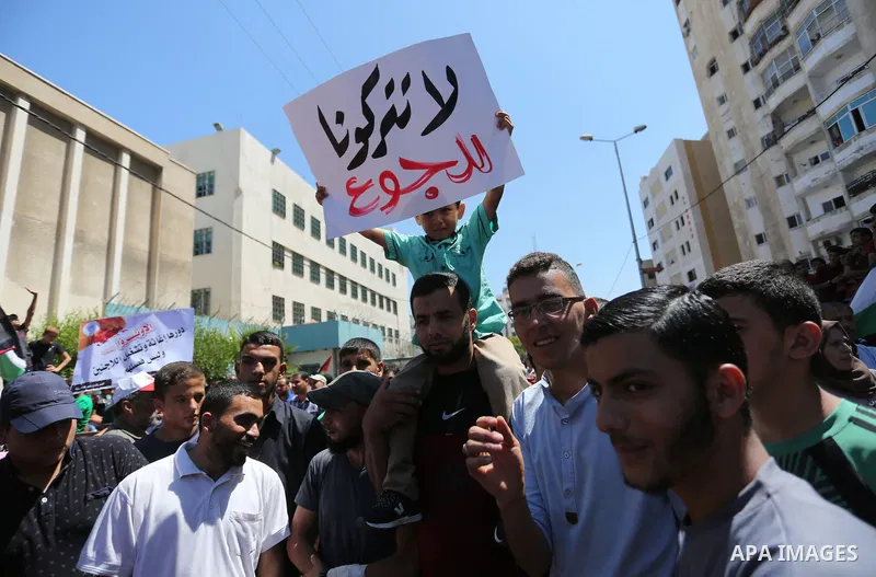 Palestinians hold banners during a demonstraion against a U.S. decision to cut aid, in front of the headquarters United Nations Relief and Works Agency (UNRWA), in Gaza City, on July 31, 2018. Photo by Ashraf Amra