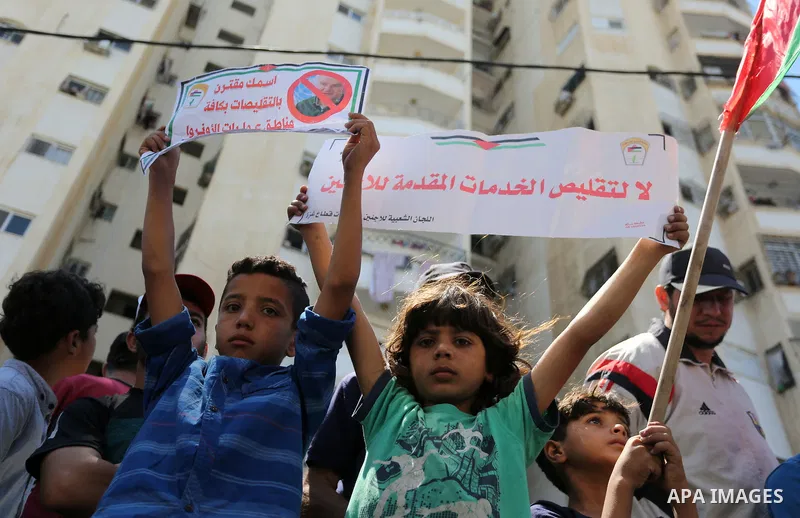 Palestinians hold banners during a demonstraion against a U.S. decision to cut aid, in front of the headquarters United Nations Relief and Works Agency (UNRWA), in Gaza City, on July 31, 2018. Photo by Ashraf Amra