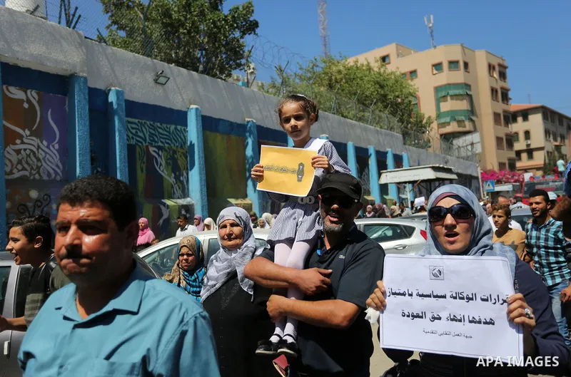Palestinians hold banners during a demonstraion against a U.S. decision to cut aid, in front of the headquarters United Nations Relief and Works Agency (UNRWA), in Gaza City, on July 31, 2018. Photo by Ashraf Amra
