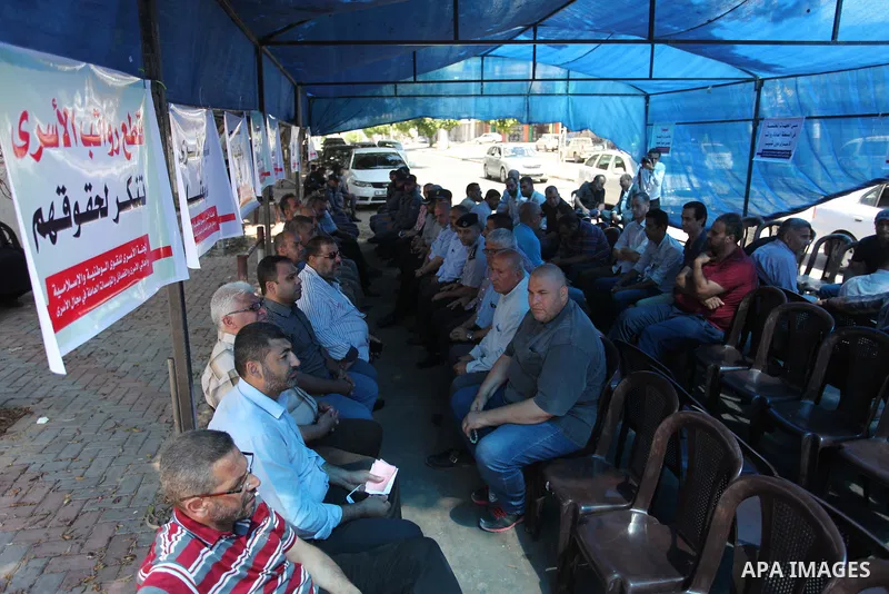 Palestinians take part in a protest to show solidarity with Palestinian prisoners are paid their salaries in Iseali jails at a tent in front of the Council of Ministers headcuarter in Gaza City, on Aug. 01, 2018. Photo b...