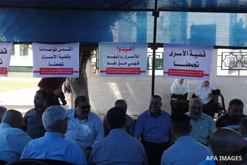 Palestinians take part in a protest to show solidarity with Palestinian prisoners are paid their salaries in Iseali jails at a tent in front of the Council of Ministers headcuarter in Gaza City, on Aug. 01, 2018. Photo b...