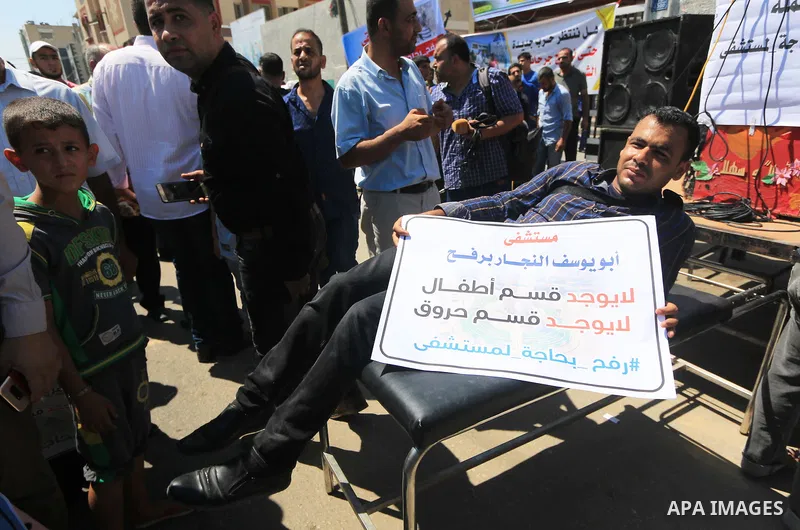Palestinians hold banners during a protest to demand the built of a hospital in Rafah in the southern Gaza strip on Aug. 01, 2018. Photo by Mahmoud Khattab