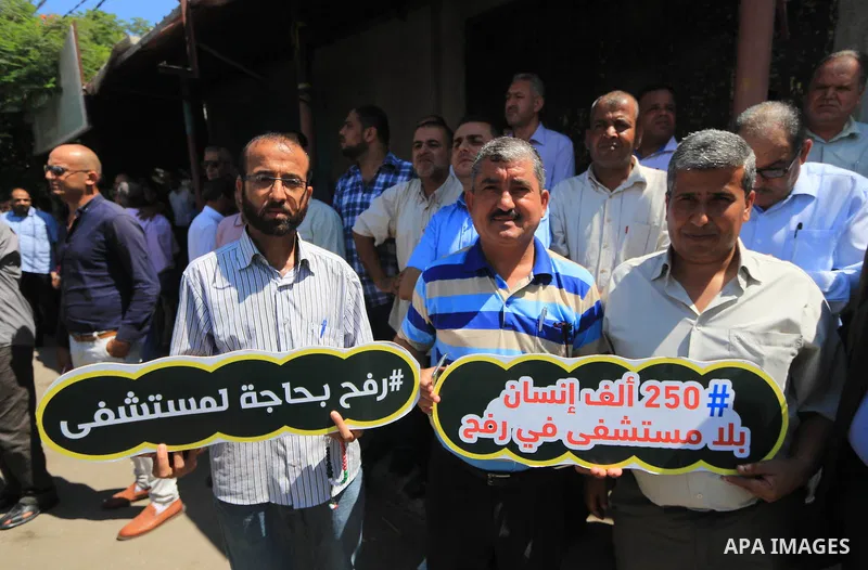 Palestinians hold banners during a protest to demand the built of a hospital in Rafah in the southern Gaza strip on Aug. 01, 2018. Photo by Mahmoud Khattab