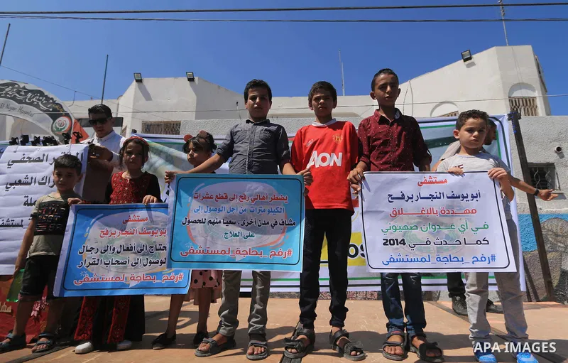 Palestinians hold banners during a protest to demand the built of a hospital in Rafah in the southern Gaza strip on Aug. 01, 2018. Photo by Mahmoud Khattab