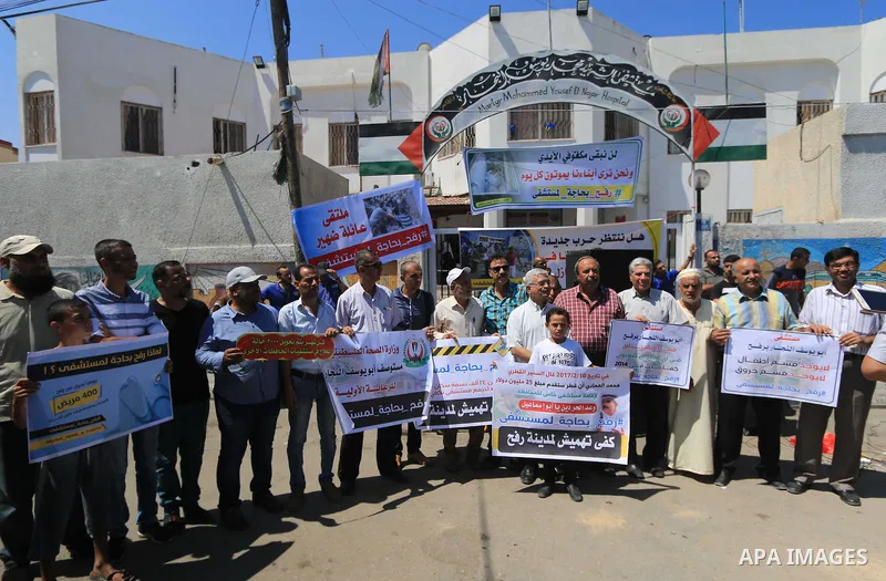 Palestinians hold banners during a protest to demand the built of a hospital in Rafah in the southern Gaza strip on Aug. 01, 2018. Photo by Mahmoud Khattab