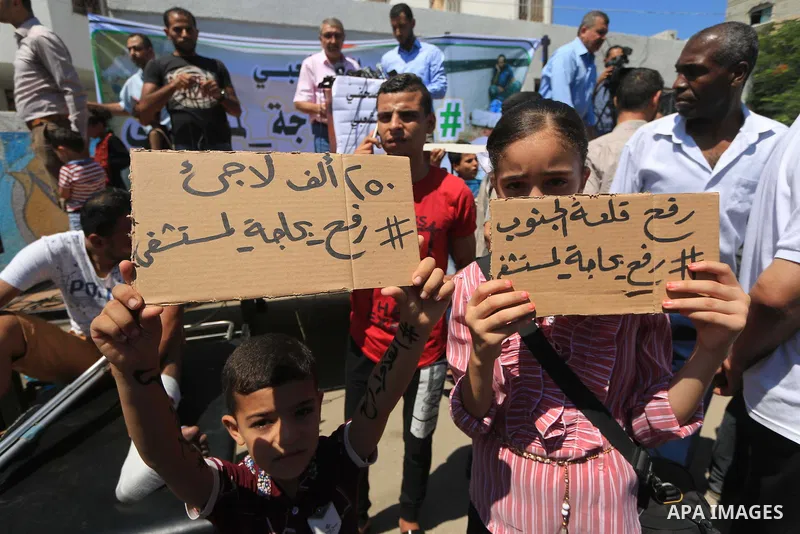 Palestinians hold banners during a protest to demand the built of a hospital in Rafah in the southern Gaza strip on Aug. 01, 2018. Photo by Mahmoud Khattab