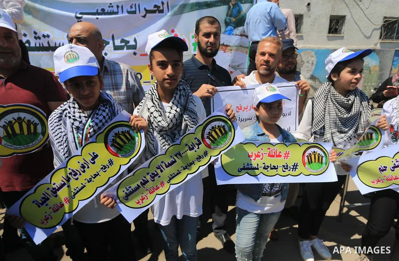 Palestinians hold banners during a protest to demand the built of a hospital in Rafah in the southern Gaza strip on Aug. 01, 2018. Photo by Mahmoud Khattab