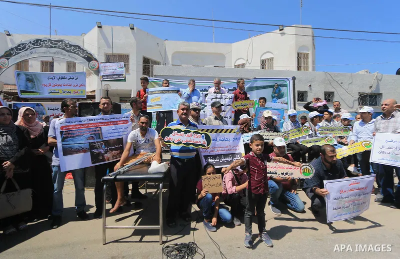 Palestinians hold banners during a protest to demand the built of a hospital in Rafah in the southern Gaza strip on Aug. 01, 2018. Photo by Mahmoud Khattab