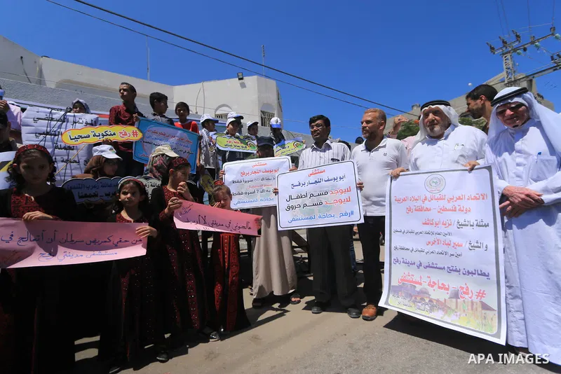 Palestinians hold banners during a protest to demand the built of a hospital in Rafah in the southern Gaza strip on Aug. 01, 2018. Photo by Mahmoud Khattab