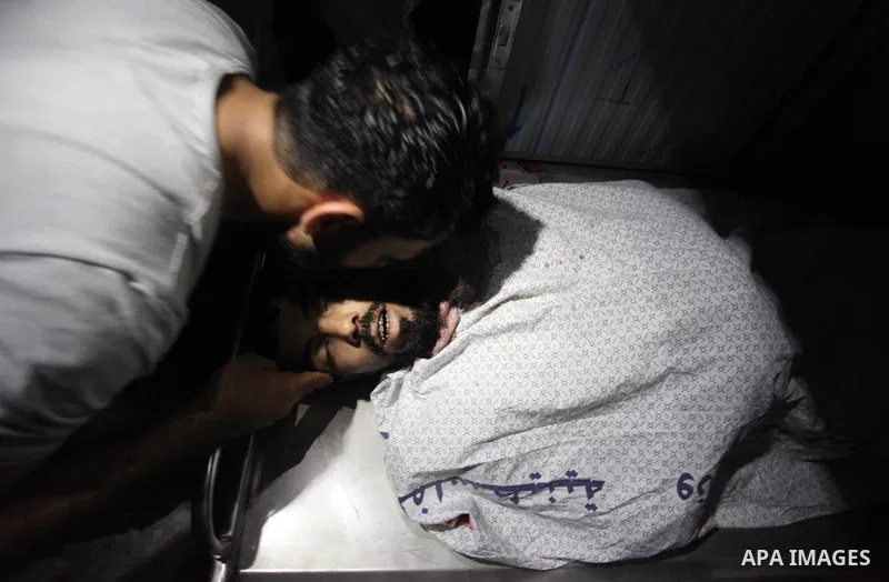 Relatives of Palestinian Ahmed Yaghi, 25, who was shot dead by Israeli troops during clashes at Gaza-Israel border mourn over his body at a morgue in a hospital in Gaza city on Aug. 03, 2018. Photo by Mahmoud Ajour