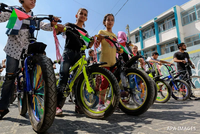 Palestinian children ride bicycles during a marathon in conjunction with a marathon in Britain, Australia, Luton, Birmingham and Coventry to support Palestinian's children and against weapon finance to Israel, in Rafah i...