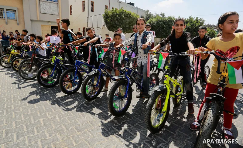 Palestinian children ride bicycles during a marathon in conjunction with a marathon in Britain, Australia, Luton, Birmingham and Coventry to support Palestinian's children and against weapon finance to Israel, in Rafah i...