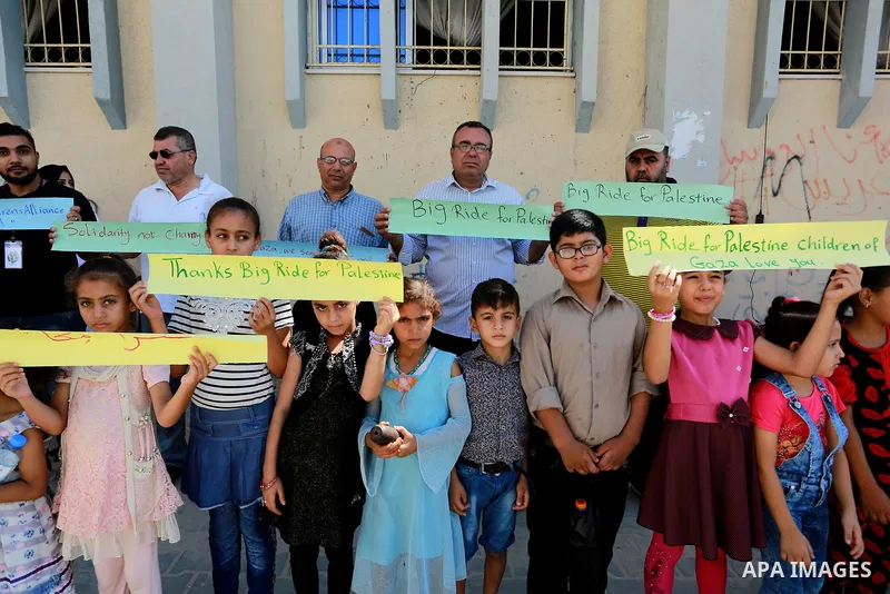 Palestinian children hold placards during a marathon in conjunction with a marathon in Britain, Australia, Luton, Birmingham and Coventry to support Palestinian's children and against weapon finance to Israel, in Rafah i...
