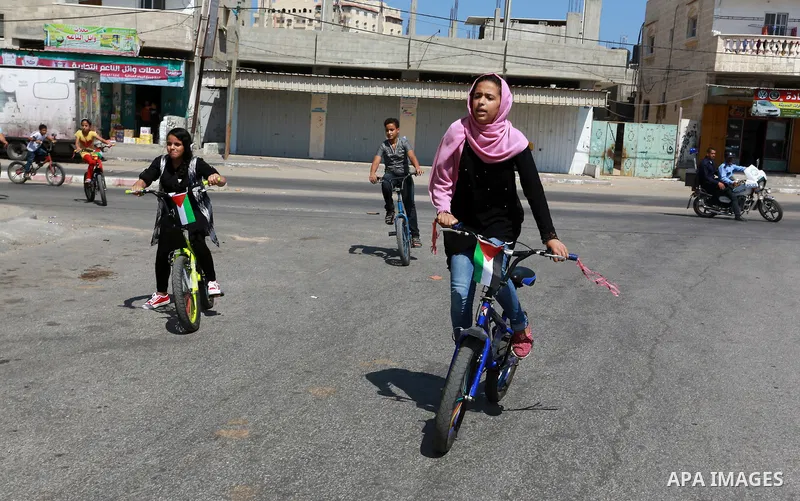Palestinian children ride bicycles during a marathon in conjunction with a marathon in Britain, Australia, Luton, Birmingham and Coventry to support Palestinian's children and against weapon finance to Israel, in Rafah i...