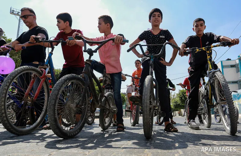 Palestinian children ride bicycles during a marathon in conjunction with a marathon in Britain, Australia, Luton, Birmingham and Coventry to support Palestinian's children and against weapon finance to Israel, in Rafah i...