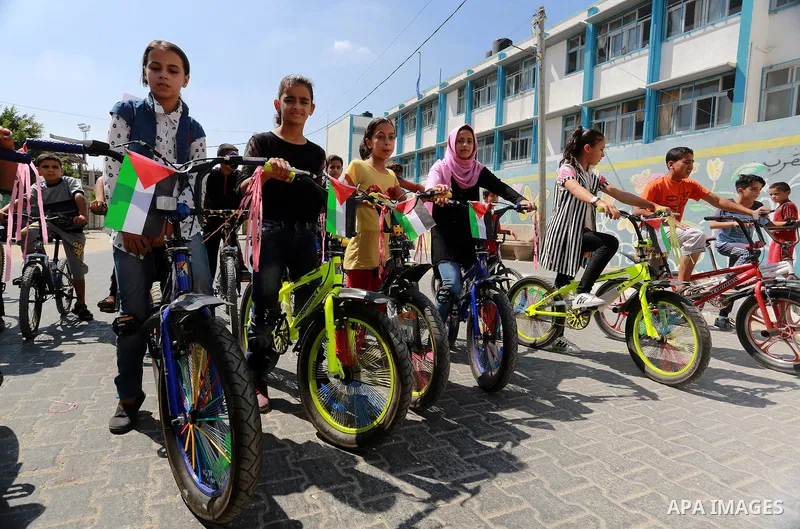Palestinian children ride bicycles during a marathon in conjunction with a marathon in Britain, Australia, Luton, Birmingham and Coventry to support Palestinian's children and against weapon finance to Israel, in Rafah i...
