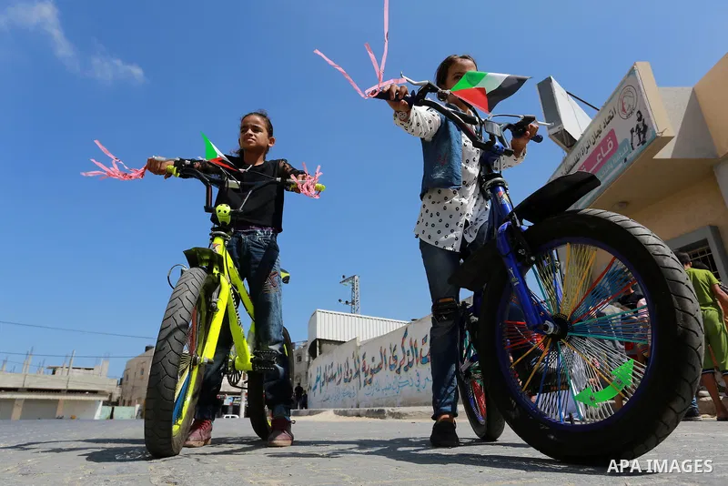 Palestinian children ride bicycles during a marathon in conjunction with a marathon in Britain, Australia, Luton, Birmingham and Coventry to support Palestinian's children and against weapon finance to Israel, in Rafah i...