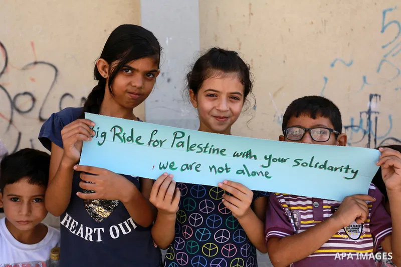 Palestinian children hold placards during a marathon in conjunction with a marathon in Britain, Australia, Luton, Birmingham and Coventry to support Palestinian's children and against weapon finance to Israel, in Rafah i...