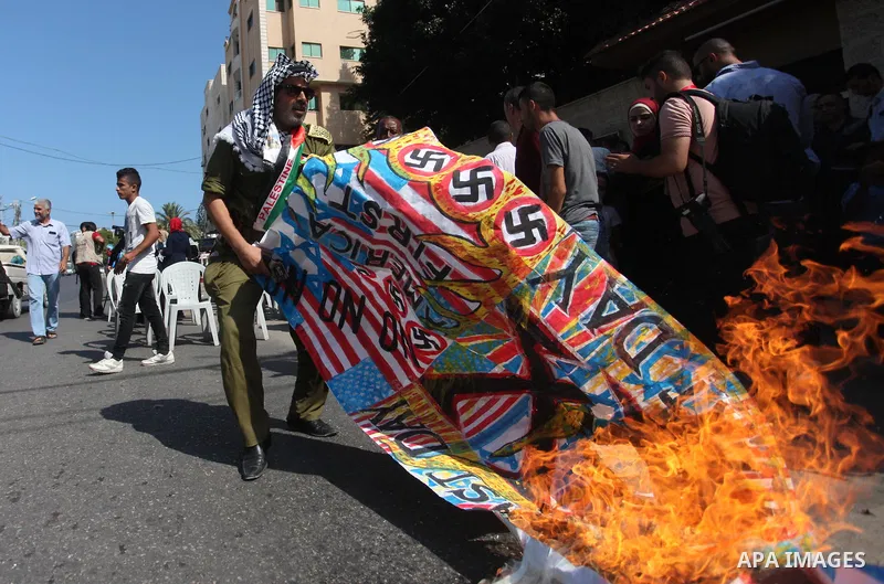 Palestinians burn an Israeli, British and U.S. flags during a protest to show solidarity with Palestinian prisoners held in Israeli jails, in front of Red cross office in Gaza city on August 6, 2018. Photo by Mahmoud Ajo...