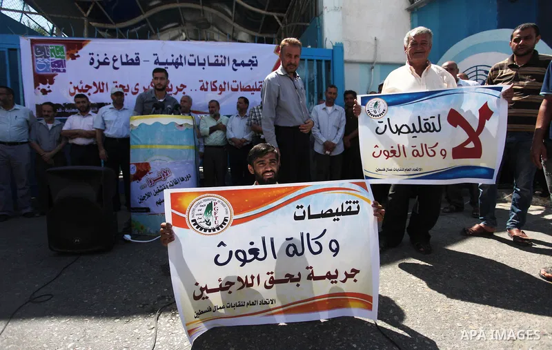 Palestinians hold banners during a protest against a U.S. decision to cut aid, in front of the headquarters United Nations Relief and Works Agency (UNRWA), in Gaza City, on August 6, 2018. Photo by Mahmoud Ajour