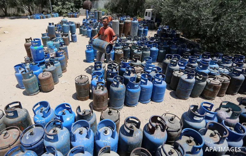 A Palestinian worker carries a gas cylinder at a gas station in Khan Younis in the southern of Gaza strip on August 6, 2018. Egypt has allowed domestic gas deliveries into the blockaded Gaza Strip for the first time, acc...