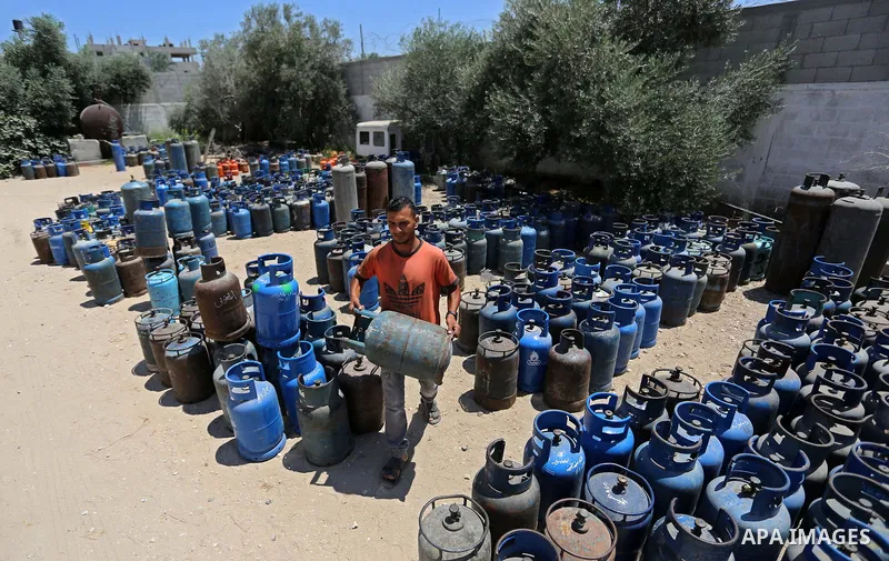 A Palestinian worker carries a gas cylinder at a gas station in Khan Younis in the southern of Gaza strip on August 6, 2018. Egypt has allowed domestic gas deliveries into the blockaded Gaza Strip for the first time, acc...