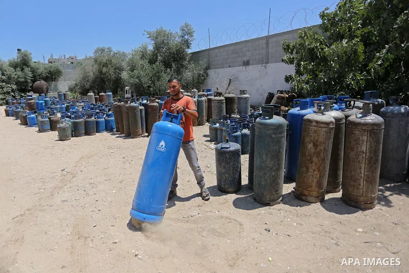A Palestinian worker carries a gas cylinder at a gas station in Khan Younis in the southern of Gaza strip on August 6, 2018. Egypt has allowed domestic gas deliveries into the blockaded Gaza Strip for the first time, acc...