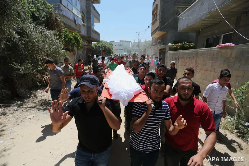 Mourners carry the body of Palestinian Ahmed al-Ayidi, 17, who died of wounds he sustained during clashes with Israeli troops, during his funeral, in the central Gaza Strip on August 6, 2018. Photo by Ashraf Amra