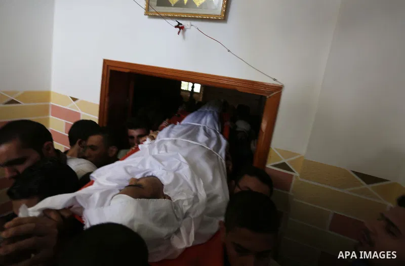 Mourners carry the body of Palestinian Ahmed al-Ayidi, 17, who died of wounds he sustained during clashes with Israeli troops, during his funeral, in the central Gaza Strip on August 6, 2018. Photo by Ashraf Amra