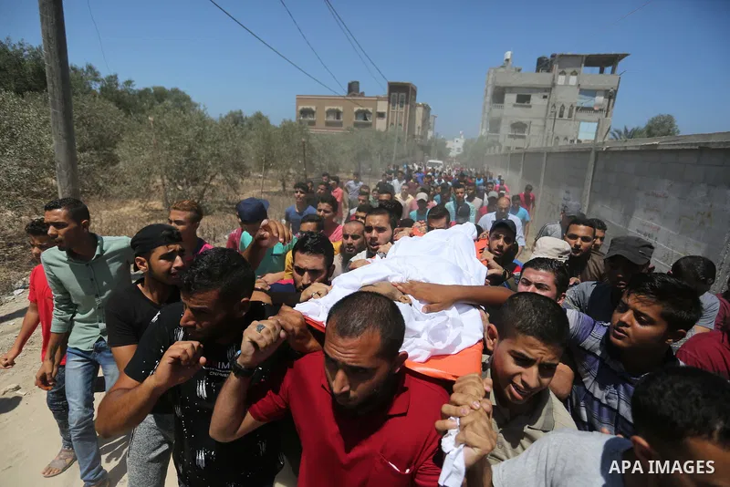 Mourners carry the body of Palestinian Ahmed al-Ayidi, 17, who died of wounds he sustained during clashes with Israeli troops, during his funeral, in the central Gaza Strip on August 6, 2018. Photo by Ashraf Amra