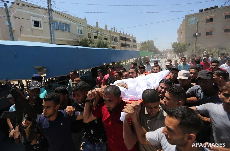 Mourners carry the body of Palestinian Ahmed al-Ayidi, 17, who died of wounds he sustained during clashes with Israeli troops, during his funeral, in the central Gaza Strip on August 6, 2018. Photo by Ashraf Amra