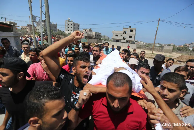 Mourners carry the body of Palestinian Ahmed al-Ayidi, 17, who died of wounds he sustained during clashes with Israeli troops, during his funeral, in the central Gaza Strip on August 6, 2018. Photo by Ashraf Amra