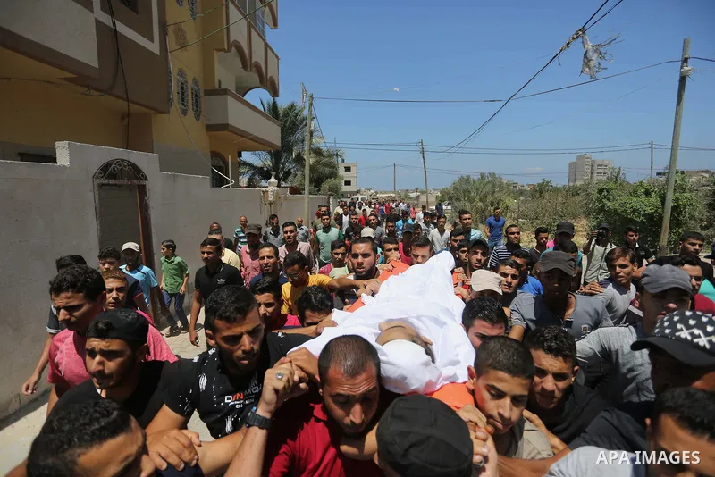 Mourners carry the body of Palestinian Ahmed al-Ayidi, 17, who died of wounds he sustained during clashes with Israeli troops, during his funeral, in the central Gaza Strip on August 6, 2018. Photo by Ashraf Amra