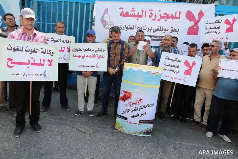 Palestinians hold placards during a protest a against the decision of United Nations Relief and Works Agency (UNRWA) reducing its services and job cuts announced by the agency, and calling for the start of the new school...