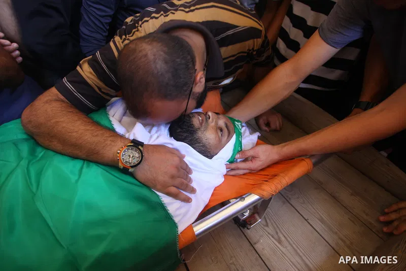 Relatives of Palestinian Hamas militant Ali al-Ghandour who was killed in an Israeli airstrike, mourn over his body during his funeral in the northern of Gaza Strip on August 9, 2018. Photo by Mahmoud Ajour