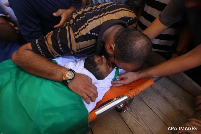 Relatives of Palestinian Hamas militant Ali al-Ghandour who was killed in an Israeli airstrike, mourn over his body during his funeral in the northern of Gaza Strip on August 9, 2018. Photo by Mahmoud Ajour