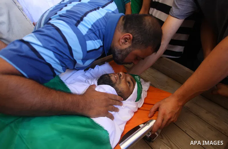 Relatives of Palestinian Hamas militant Ali al-Ghandour who was killed in an Israeli airstrike, mourn over his body during his funeral in the northern of Gaza Strip on August 9, 2018. Photo by Mahmoud Ajour