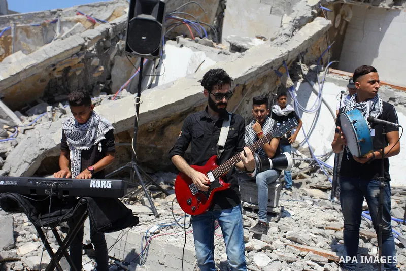 Members of a Palestinian musical band perform on the rubble of Said al-Mishal Cultural Center following an Israeli air strike destroyed it on the previous day, in Gaza city on Aug. 10, 2018. Photo by Mahmoud Ajour