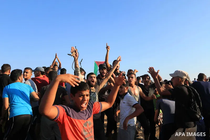 Palestinian protesters gather during clashes with Israeli troops in tents protest where Palestinians demand the right to return to their homeland at the Israel-Gaza border, in Al-Bureij in the center of Gaza Strip on Aug...