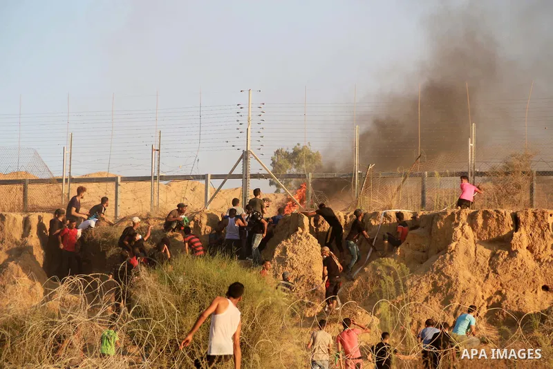 Palestinian protesters gather during clashes with Israeli troops in tents protest where Palestinians demand the right to return to their homeland at the Israel-Gaza border, in Al-Bureij in the center of Gaza Strip on Aug...